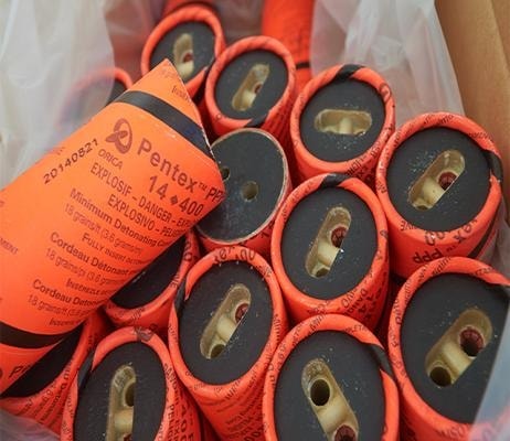 Orange-wrapped Orica Pentex cast boosters packed in a bulk liner, each showing its moulded detonator well